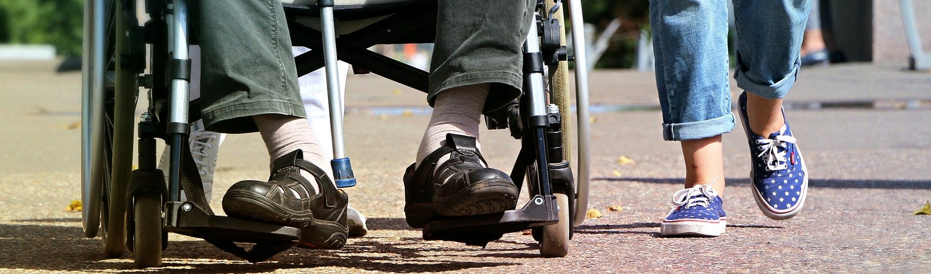 senior in wheelchair beside walking person